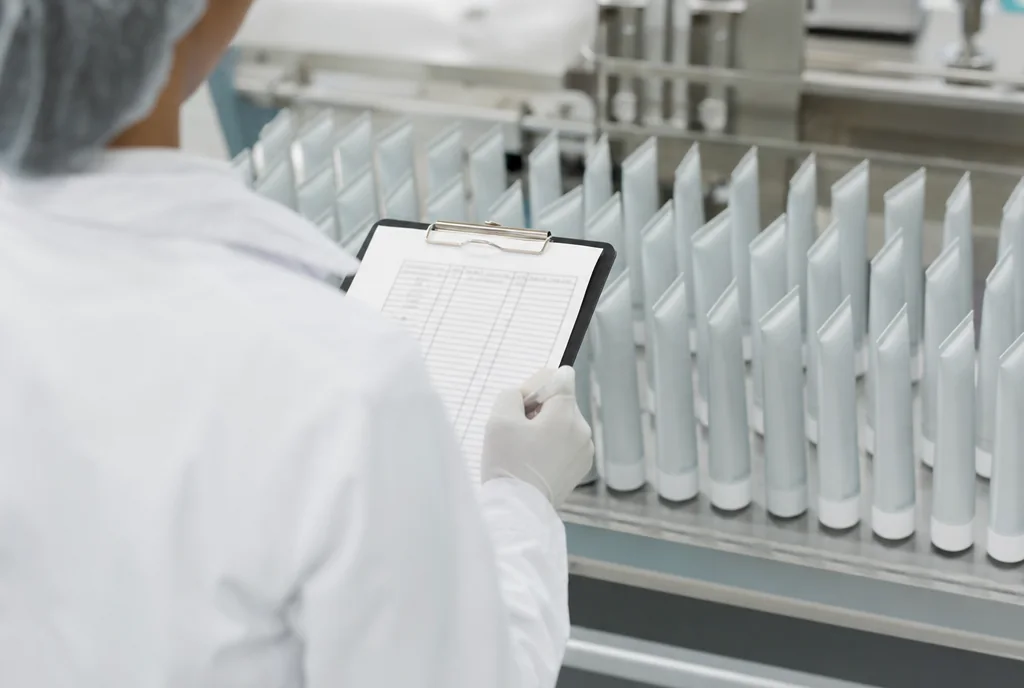 Quality inspector with a clipboard checking rows of finished products on a factory inspection bench